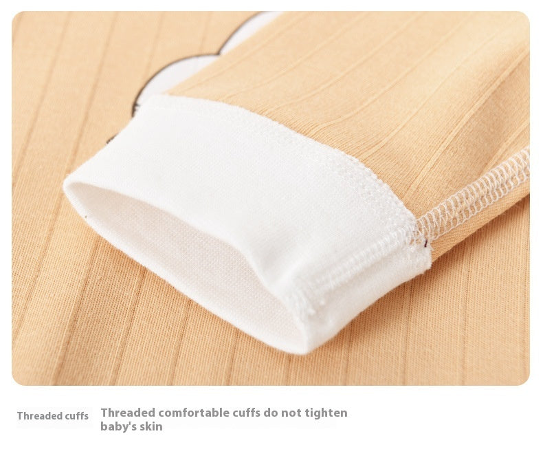 Close-up of beige fabric with white threaded cuffs on a wooden surface.