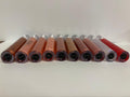 Row of lip gloss tubes on a white surface with a light gray background
